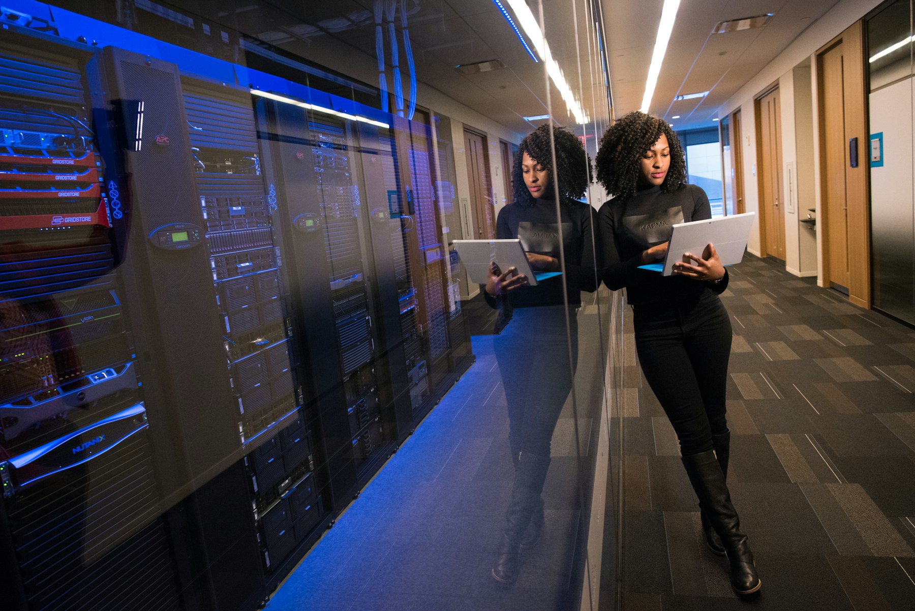 Engineer reviewing infrastructure beside server racks in a data center corridor