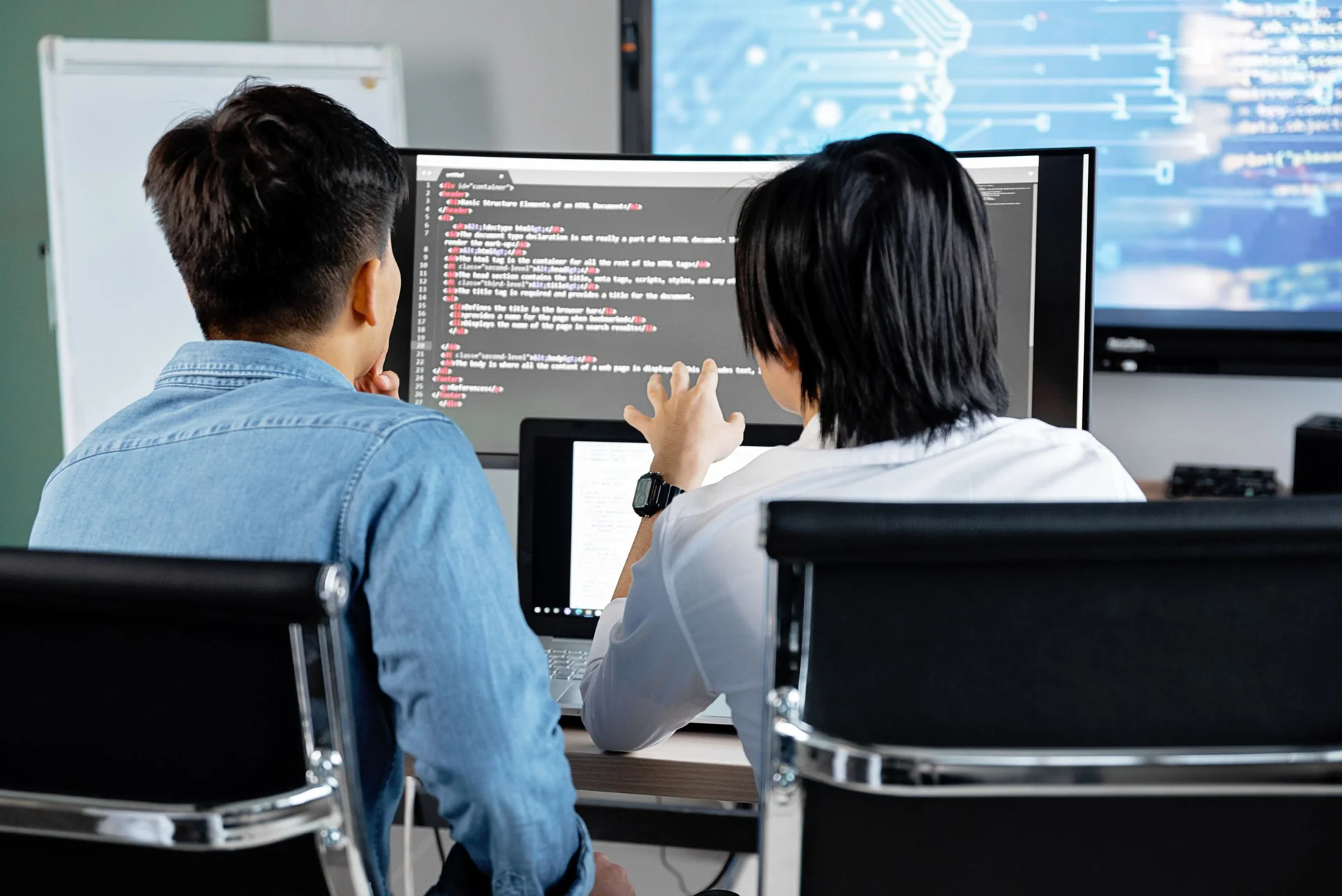 Software engineers reviewing code together at a desktop workstation