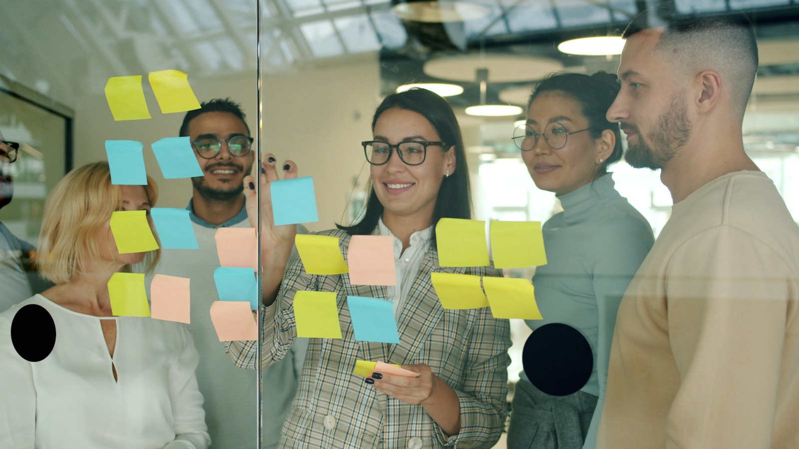 Software team planning work together with notes on a glass wall