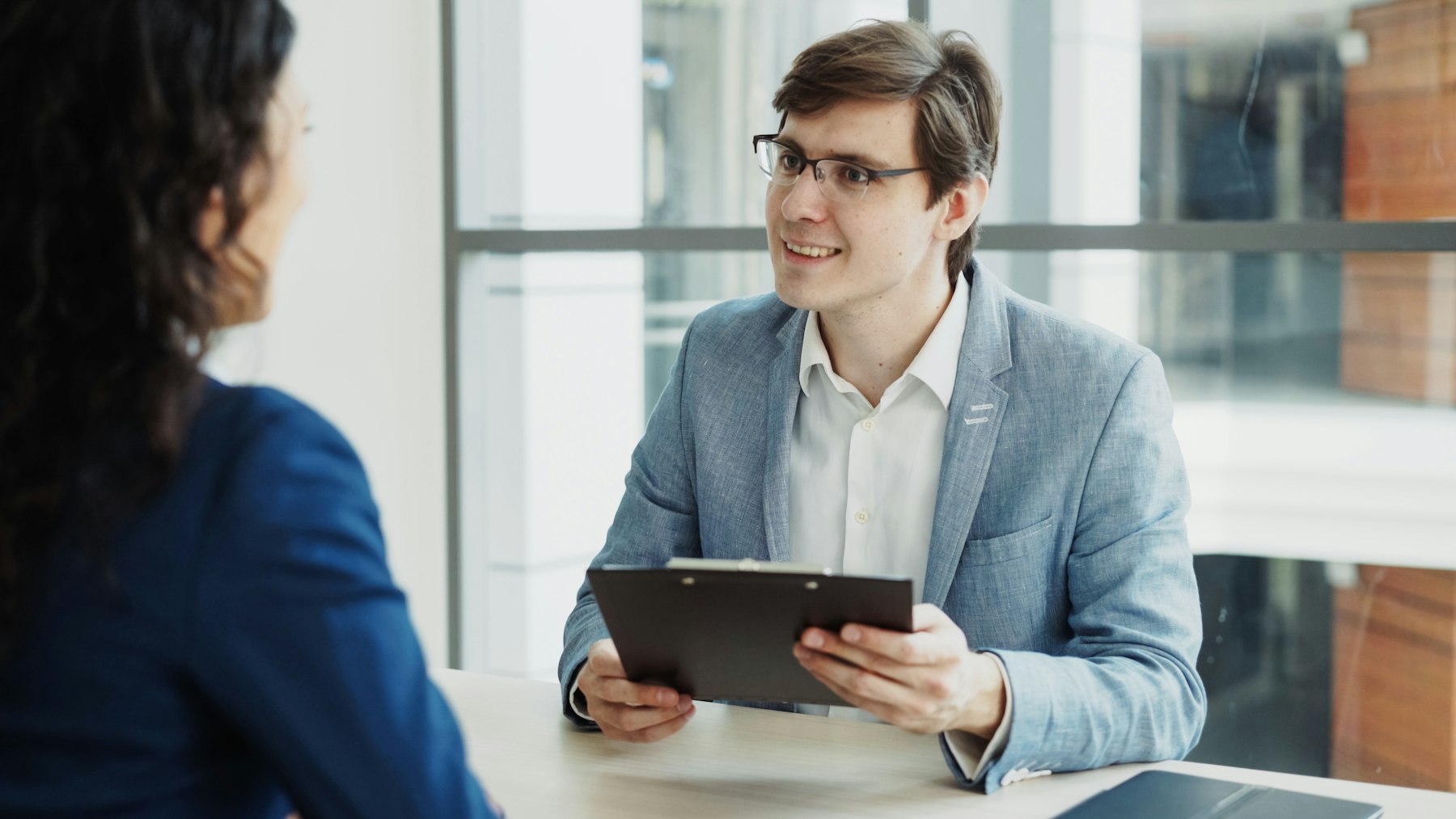 Two professionals in a relaxed interview conversation in a modern office