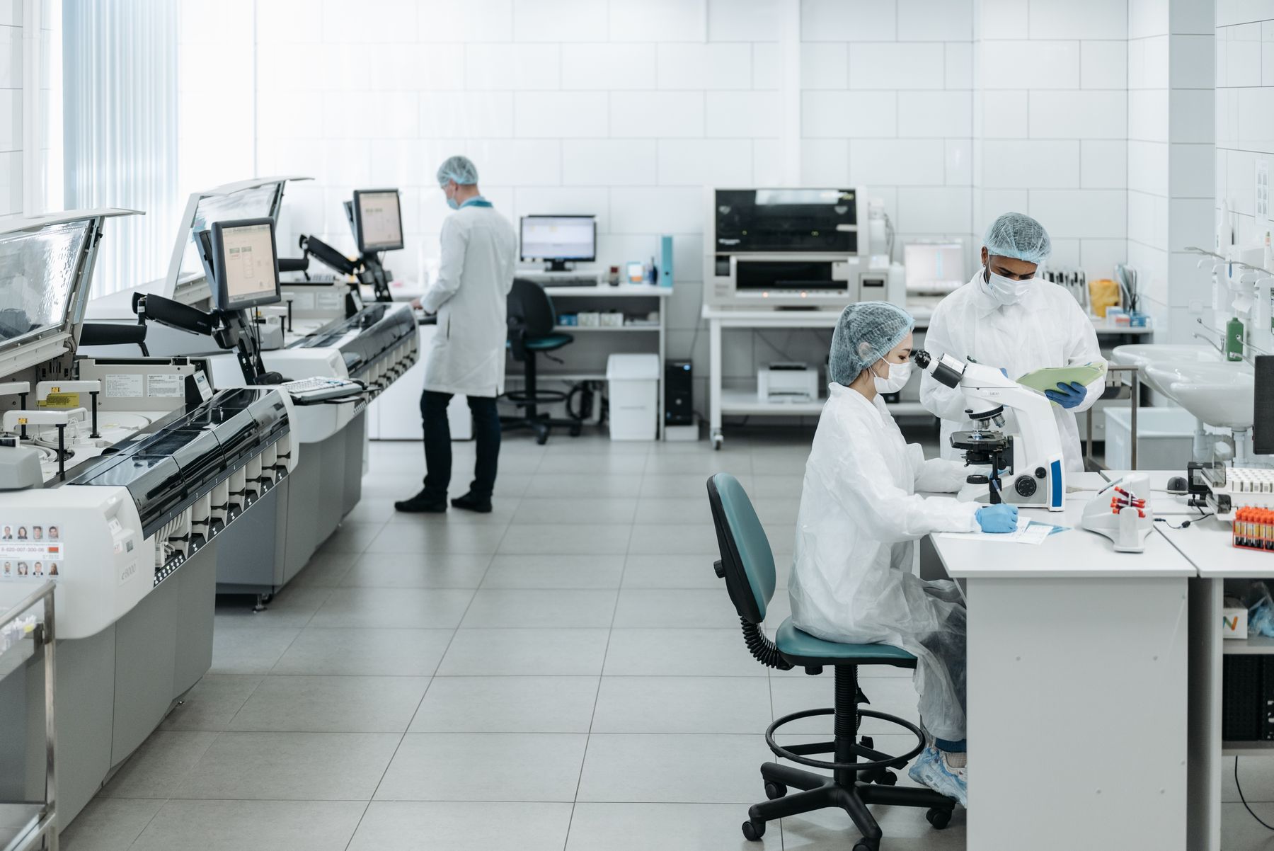 Researchers using a microscope and clinical testing equipment in a laboratory