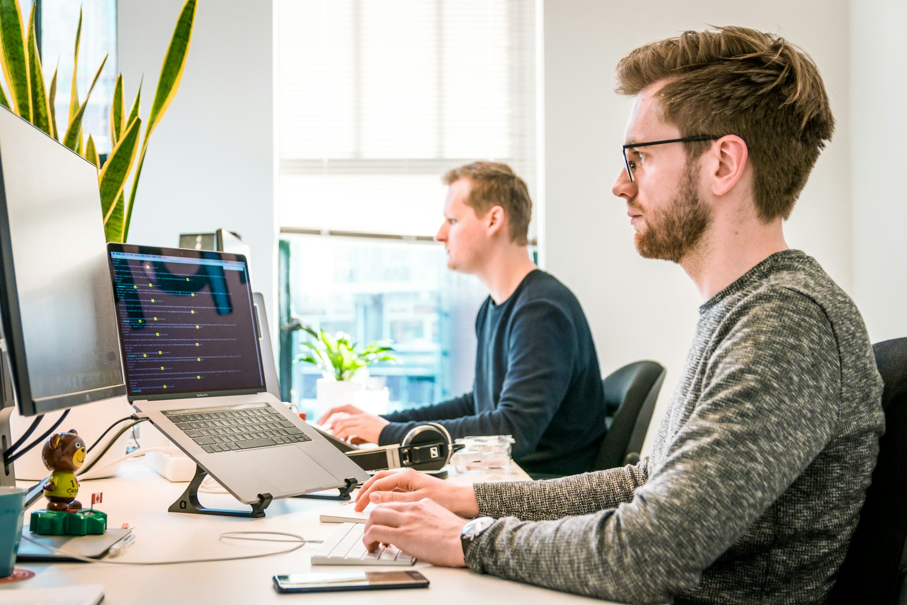 Two software engineers working together at desks in a bright office